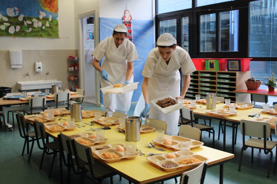 El personal de cuina posant menjar a una aula infantil a l'escola Thau. FOTO: Cedida