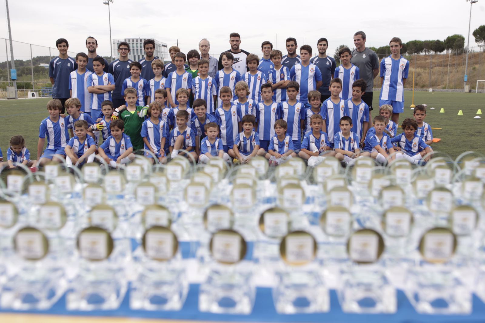 Els nois de l'escola de futbol i David López, a la part superior, i els trofeus, a l'inferior. FOTO: Artur Ribera