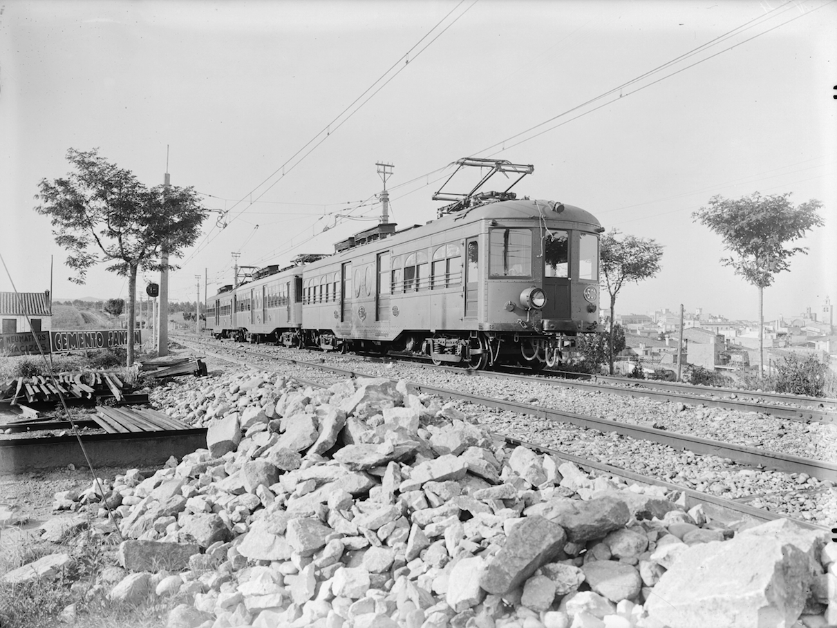 Un tren a punt d'entrar a l'estació de Sant Cugat, a la dreta de tot es pot veure el Monestir de Sant Cugat FOTO: Arxiu històric d'FGC 