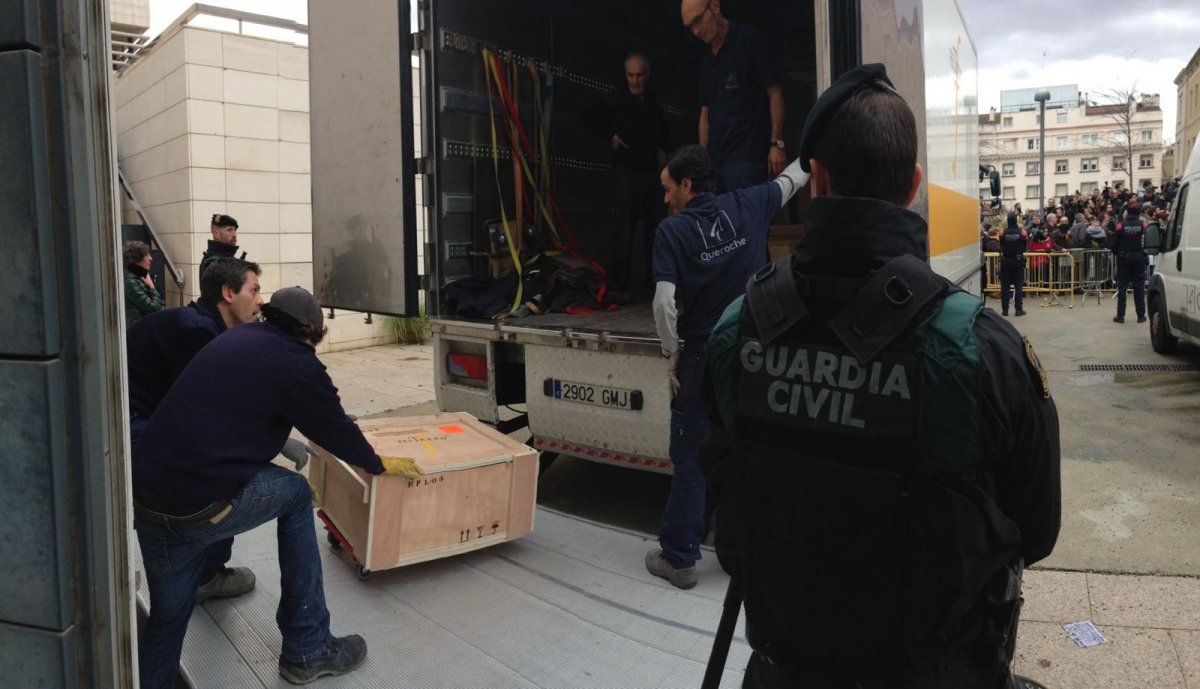Tècnics carregant les obres sota la vigilància de la Guàrdia Civil. FOTO: El Món