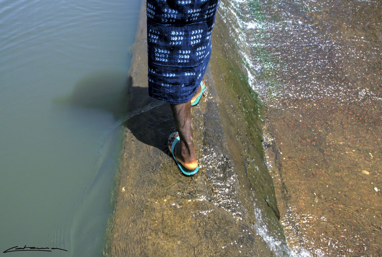 Carles Cabanas  “2001, Mali. Les últimes pluges havien augmentat el cabal d’alguns rierols i l’aigua corria per sobre. Vaig posar-me darrere d’una dona dogon i, tot caminant i mirant on posava els peus, vaig trobar aquesta foto”.