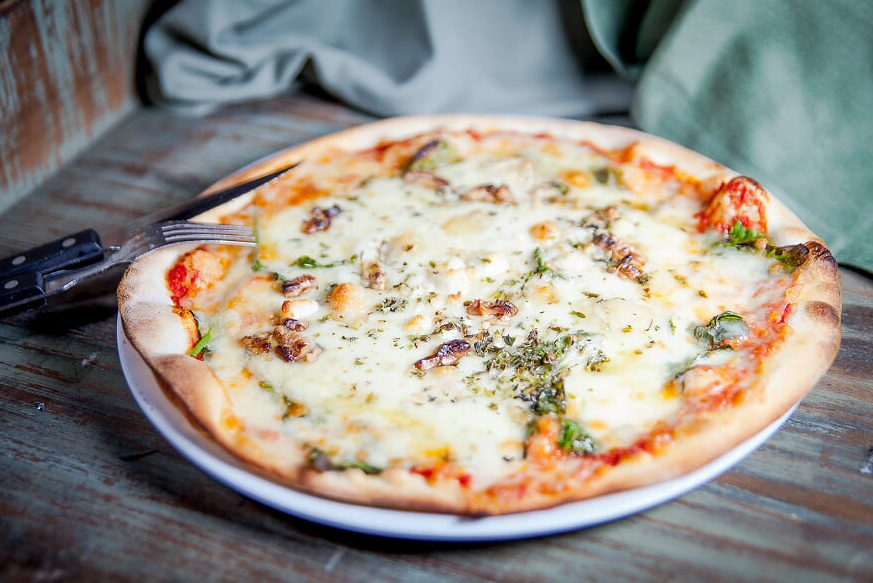 Pizza Clotilda, elaborada amb espinacs frescos, formatge de cabra, nous, mel, mozzarella, tomàquet i orenga
