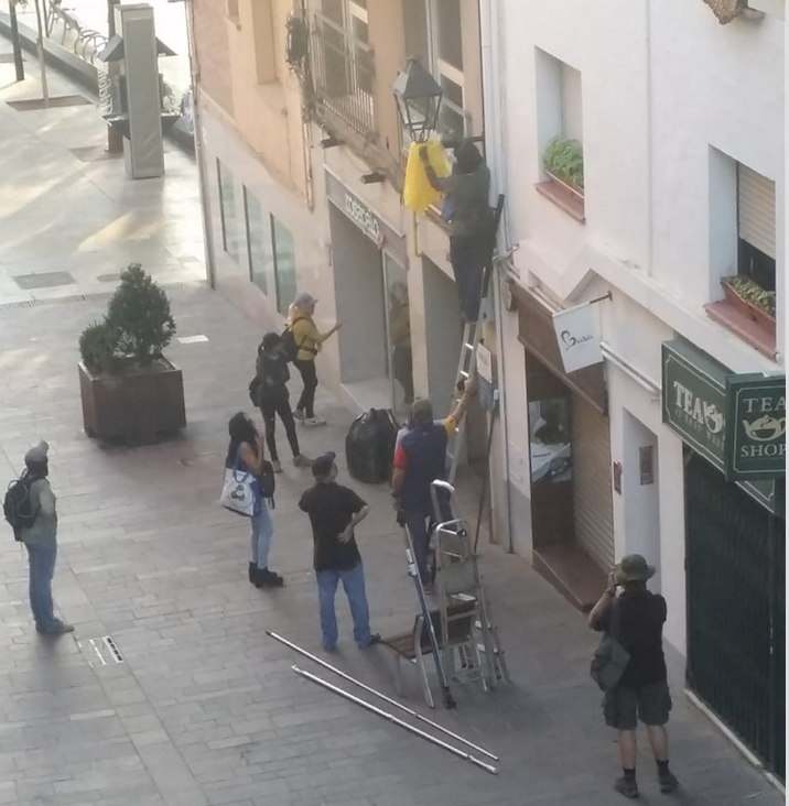 Un grup de persones retira llaços grocs al carrer Major. FOTO: Cedida