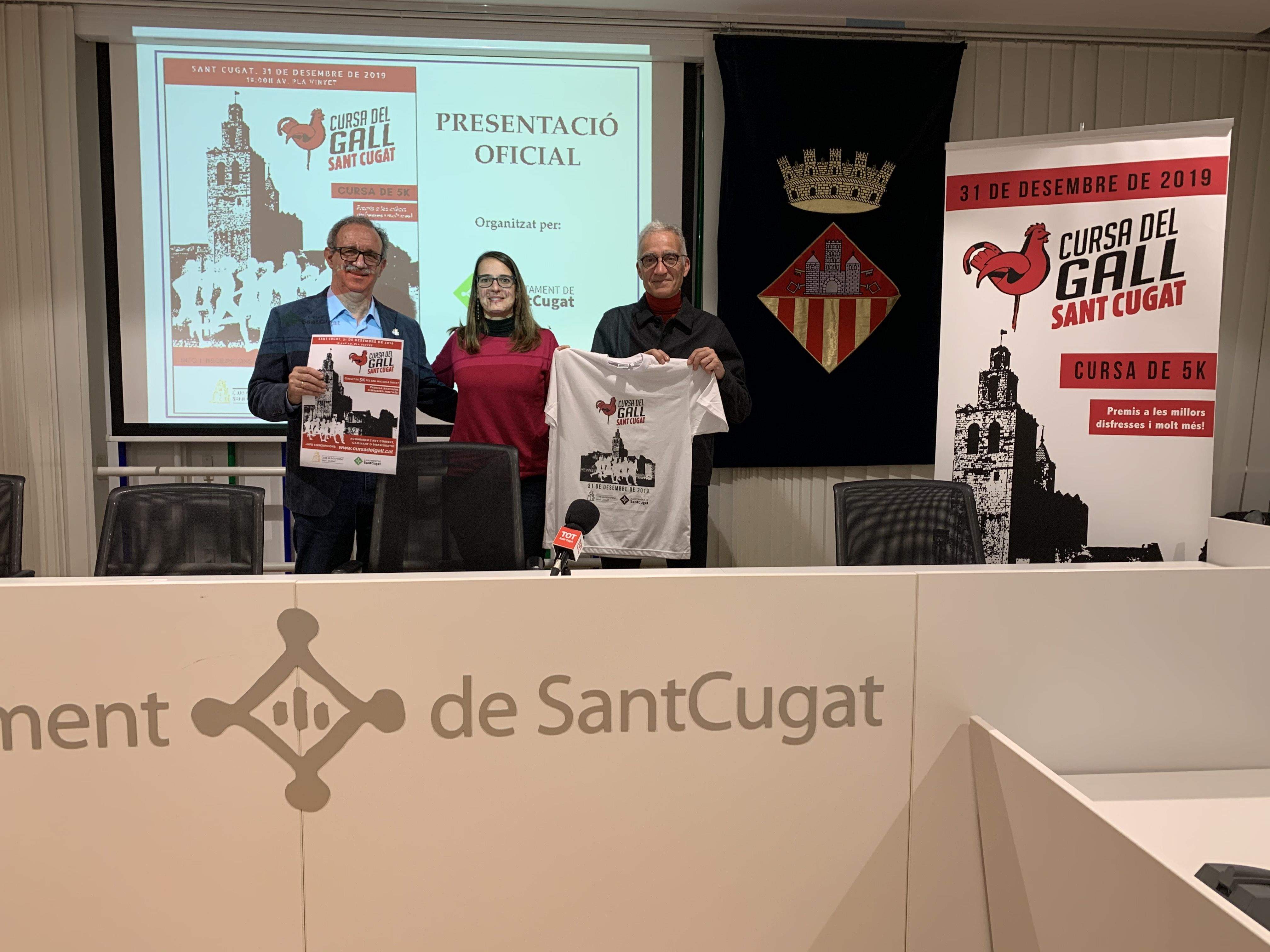 Silvano Bendinelli, Gemma Aristoy i Manel González, amb la samarreta i el cartell oficial de la 1a Cursa del Gall. FOTO: Àlex López Puig