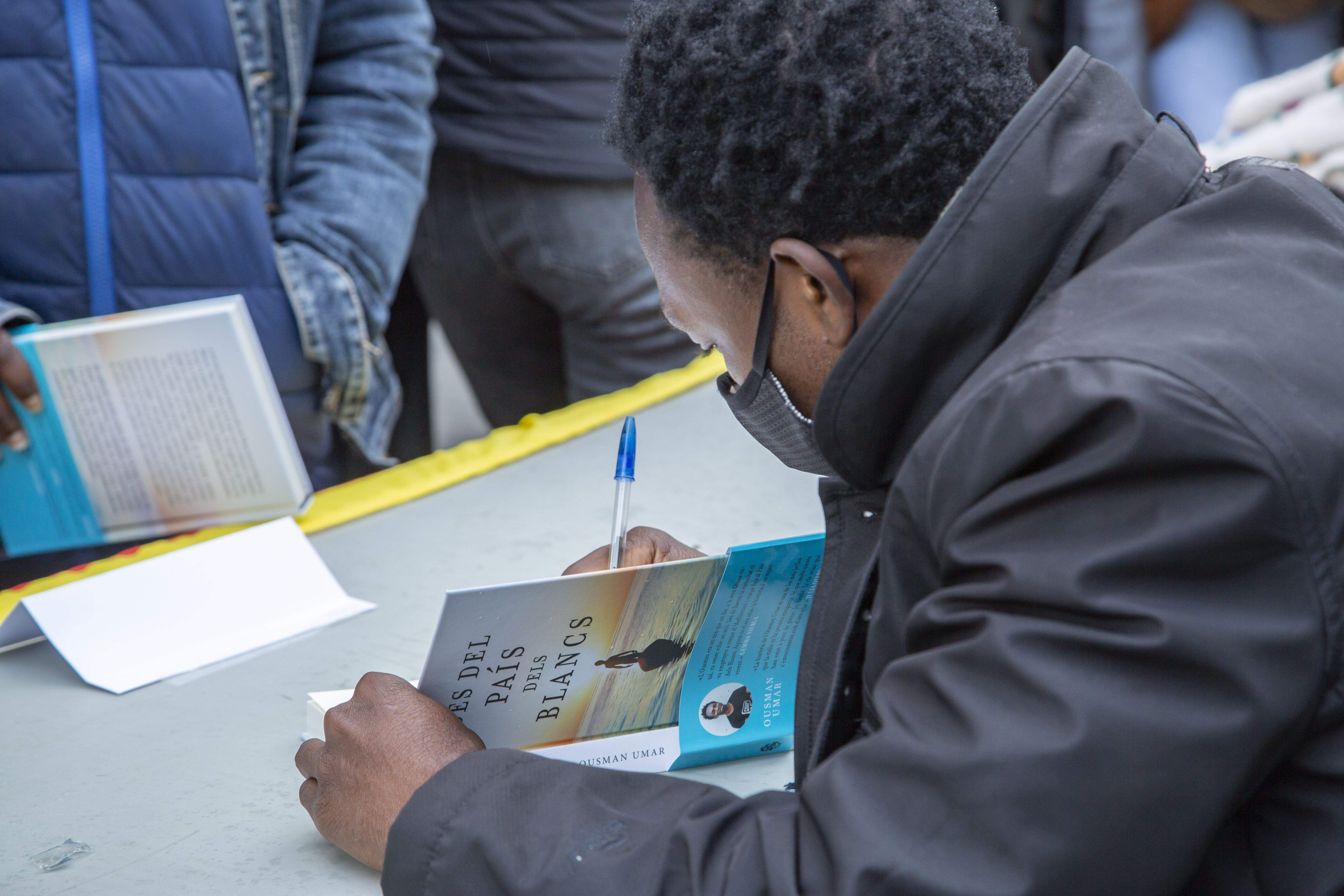 Ousman Umar signant un exemplar del seu llibre 'Des del país dels blancs' a la Taula d'Escriptors del TOT Sant Cugat FOTO: A. Bravo