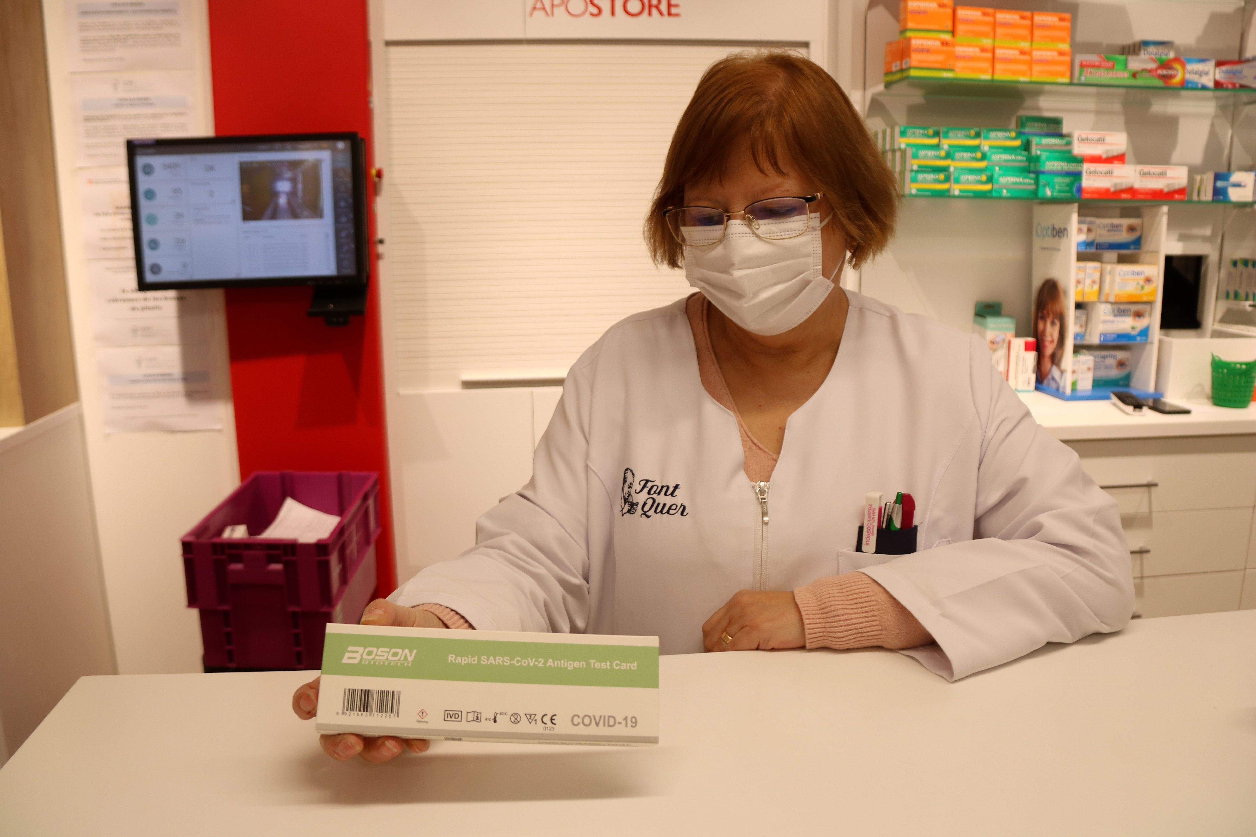 Una farmacèutica amb una caixa d'un test d'antigen en una farmàcia. FOTO: Mar Rovira (ACN)
