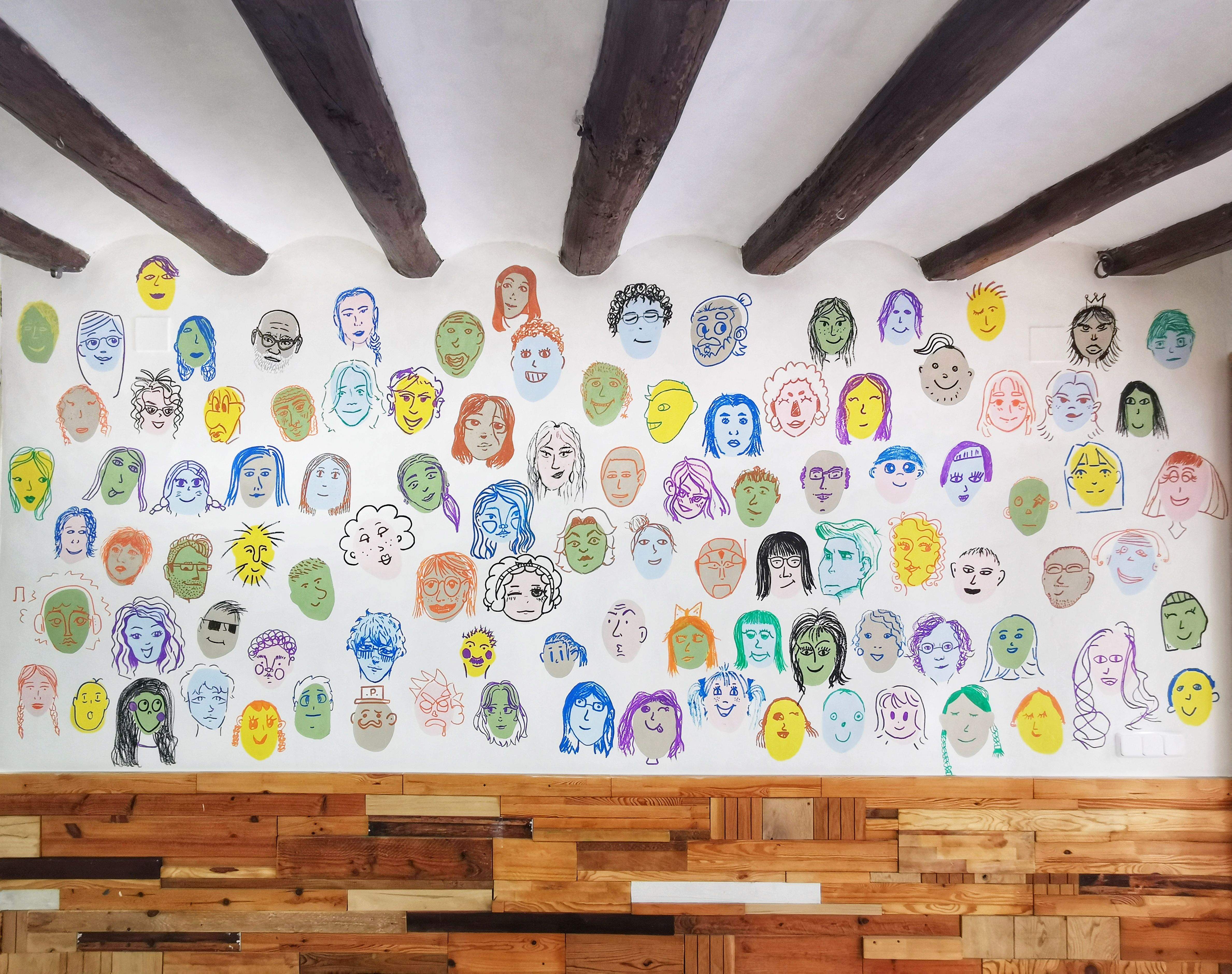 Mural col·lectiu amb 100 cares pintades per la comunitat de Pou d'Art. FOTO: Cedida