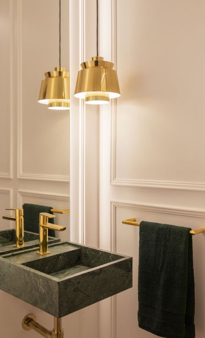 Les peces daurades afegeixen un contrast brillant i elegant al conjunt en un lavabo, i de parets blanques amb panells FOTO: Cedida