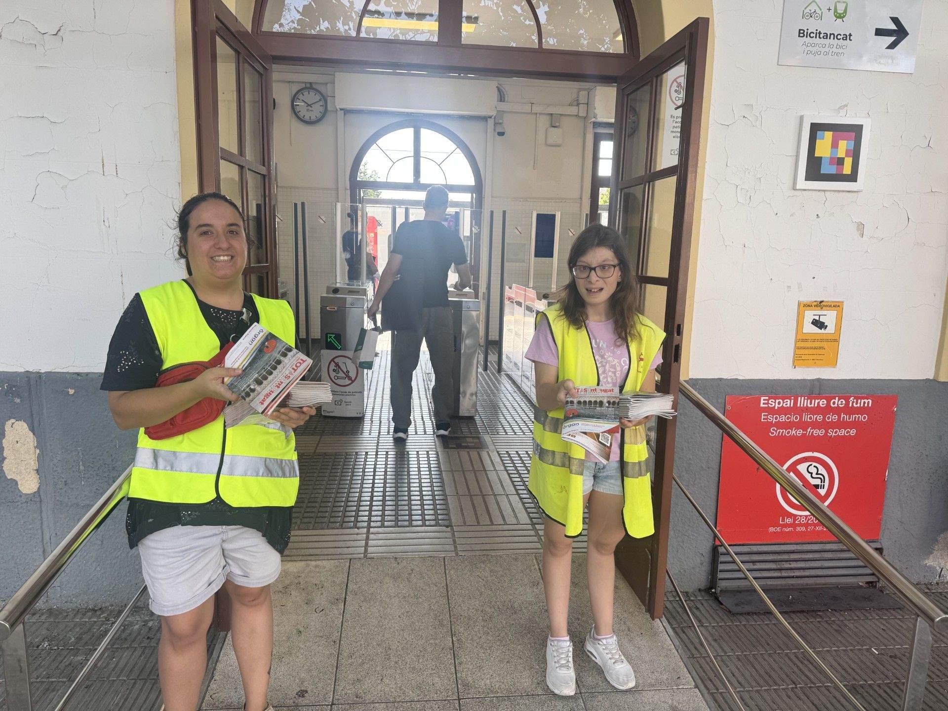 Dues persones del Jeroni de Moragas repartint la revistes del TOT Sant Cugat a l'estació de FGC de Valldoreix. FOTO: TOT Sant Cugat