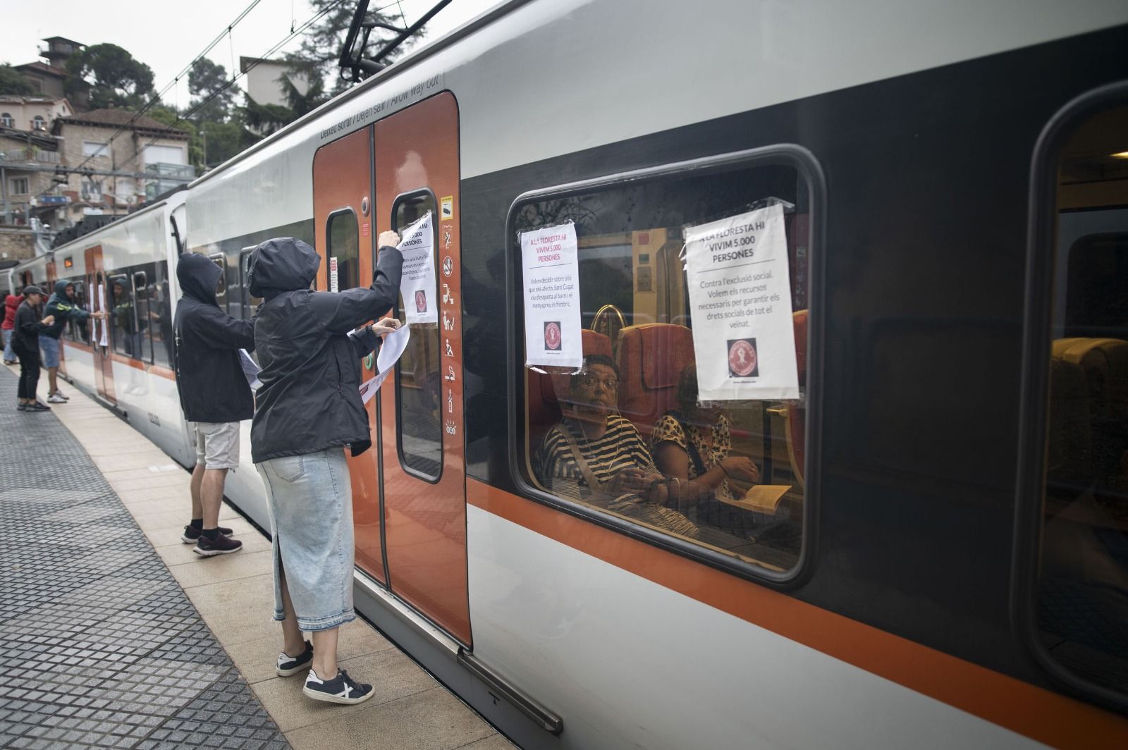 Membres de l'Ateneu Popular de la Floresta penjant cartells en els trens dels FGC. FOTO: Cedida