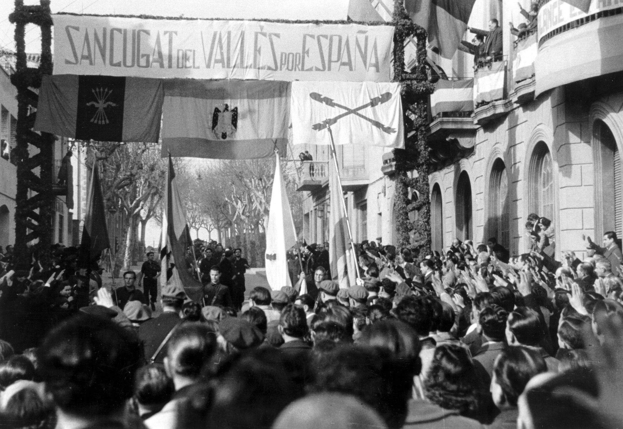 Desfilada falangista pel carrer Rius i Taulet, davant Cal Barbany. Sant Cugat. [1941], Fons Cabanas. Arxiu Municipal de Sant Cugat